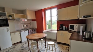A compact kitchen with a gas stove, microwave, and a small refrigerator. There is a window providing natural light and a view of greenery outside. - Gîte des Fournelles - SAINT-LAGER (SAINT-LAGER)