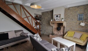Ein gemütliches Wohnzimmer mit einer Holztreppe, einer Steinwand, einem Kamin und einem weißen Tisch.