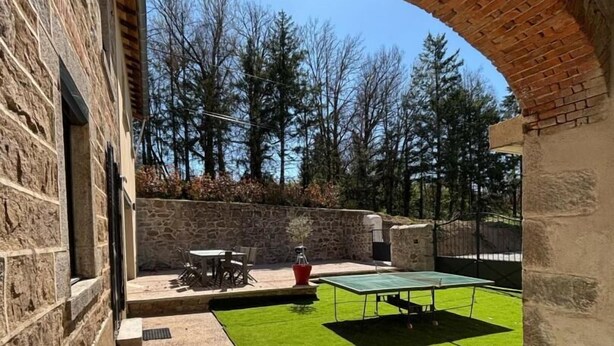 An outdoor patio with a ping pong table, a stone wall, and a grassy area. - Gite du Bobet - CHAMBOST LONGESSAIGNE (CHAMBOST LONGESSAIGNE)