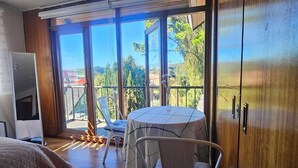Un dormitorio con una cama grande, televisión, balcón con mesa y sillas, y vistas al exterior.