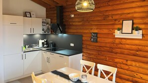 A kitchen with white cabinets, a black countertop, a hanging light fixture, and a chalkboard with a message. - VACATION HOUSE VACATION APARTMENT EIFEL-ARDENNEN LOG CABIN VIEBIGHAUS (Buchet)