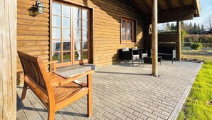 A wooden cabin with a brick patio, a bench, and a table with chairs. - VACATION HOUSE VACATION APARTMENT EIFEL-ARDENNEN LOG CABIN VIEBIGHAUS (Buchet)