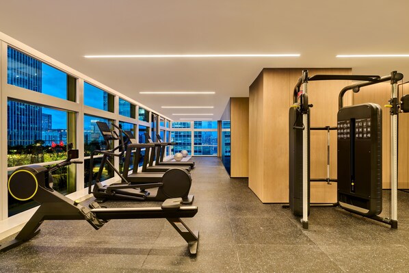 A gym with cardio machines, weightlifting equipment, and large windows offering city views. - Doubletree By Hilton Shenzhen Bay (Shenzhen)