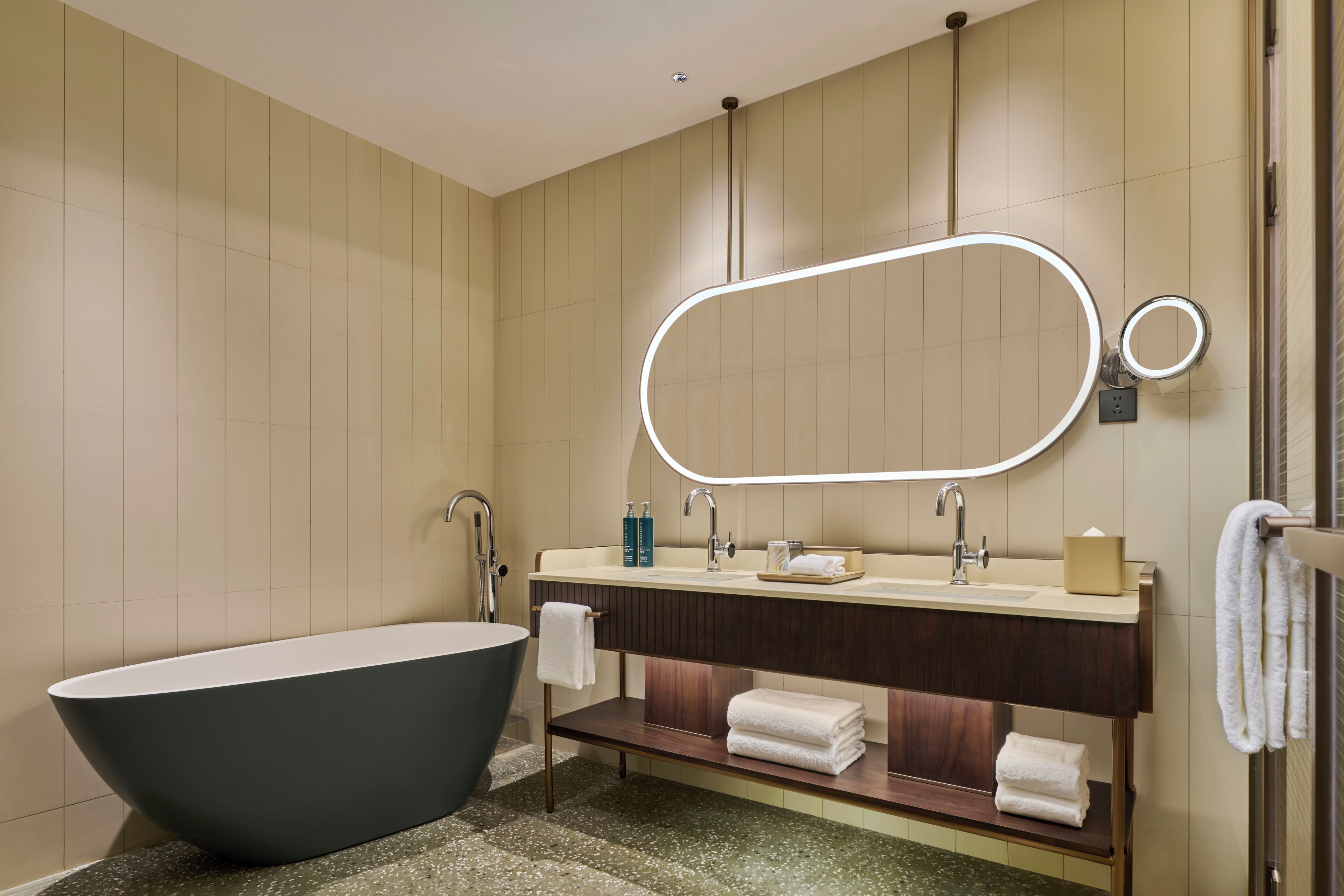 A modern bathroom with a freestanding bathtub, a vanity with a mirror, and a towel rack.