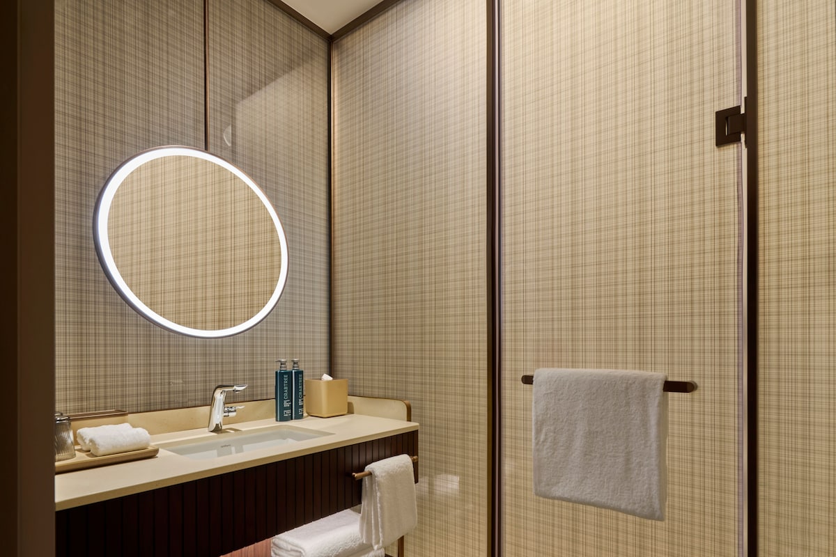 A bathroom with a mirror, sink, towel rack, and a towel hanging on the wall.