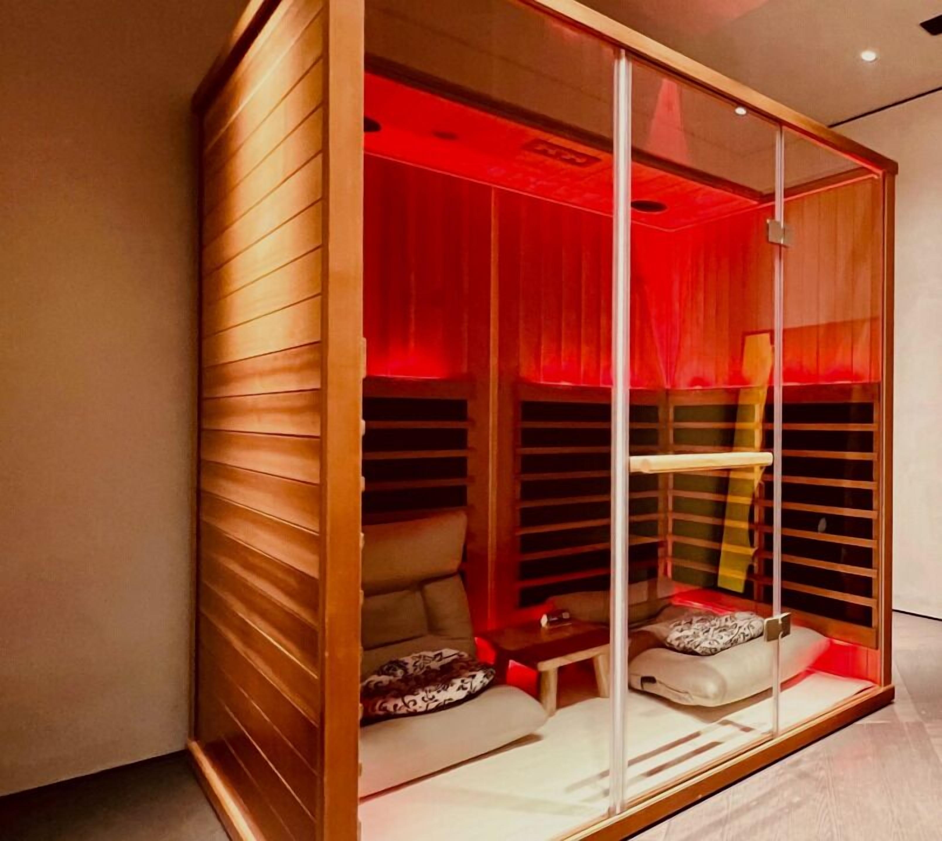 Ein moderner, abgeschlossener Sitzbereich mit Holzfassade und roter Innenraumbeleuchtung.