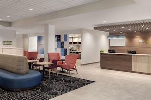 A hotel reception area with a modern design, featuring a reception desk, seating area with chairs, and a wall with the hotel's logo. - Home2 Suites By Hilton Vaughan Toronto On (Vaughan)