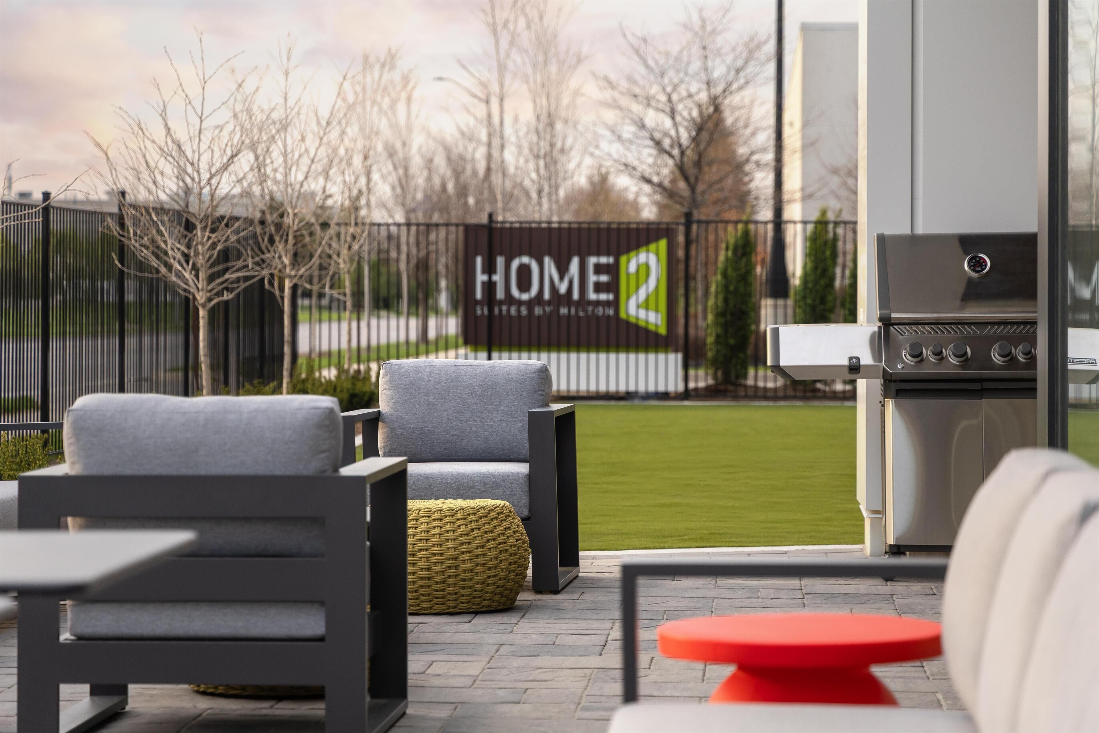 Un patio con mobiliario exterior, una parrilla y vistas a una propiedad privada.