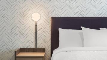 Una cama bien hecha con ropa blanca, una lámpara de noche redonda y una mesita de noche de madera.