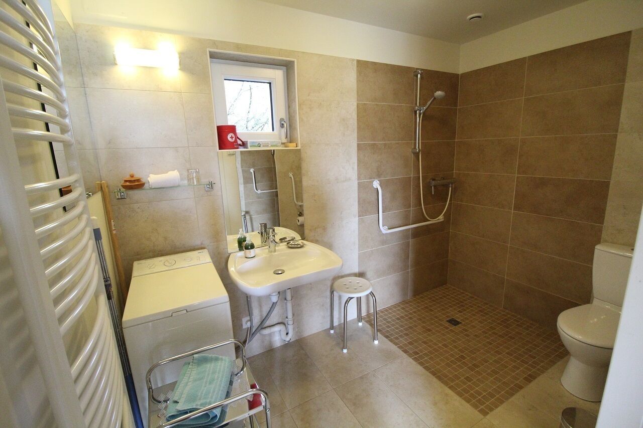 A bathroom with a shower, toilet, sink, and a towel rack.