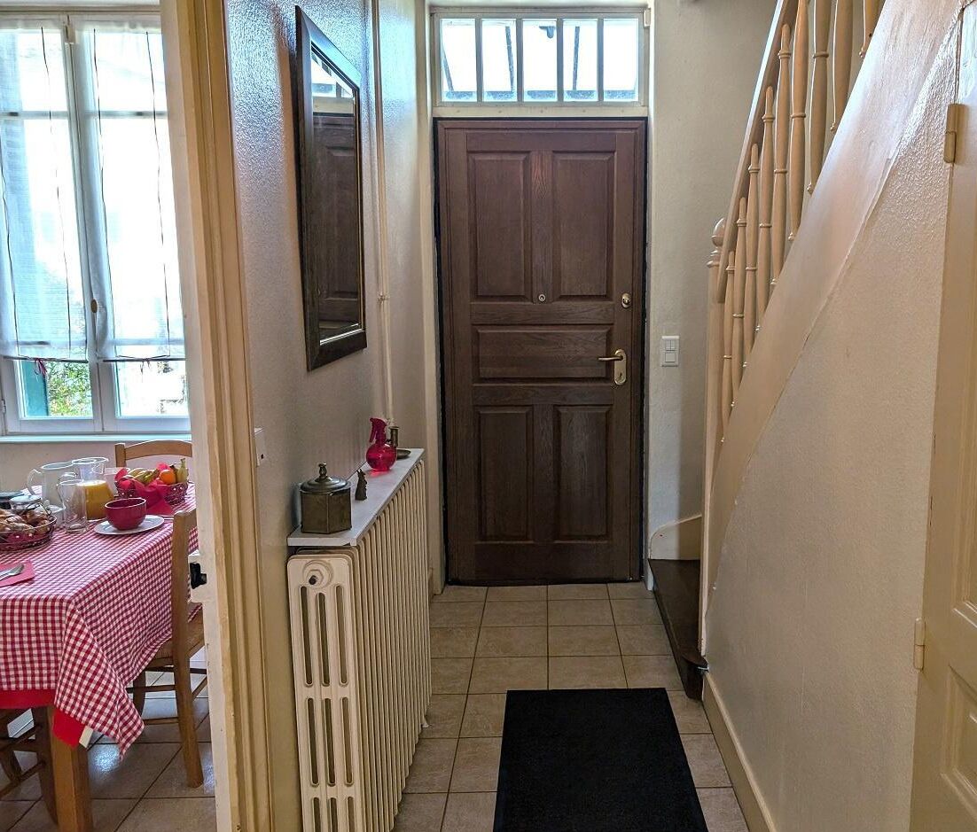 Um corredor estreito com porta de madeira, um radiador e uma mesa com itens de café da manhã.