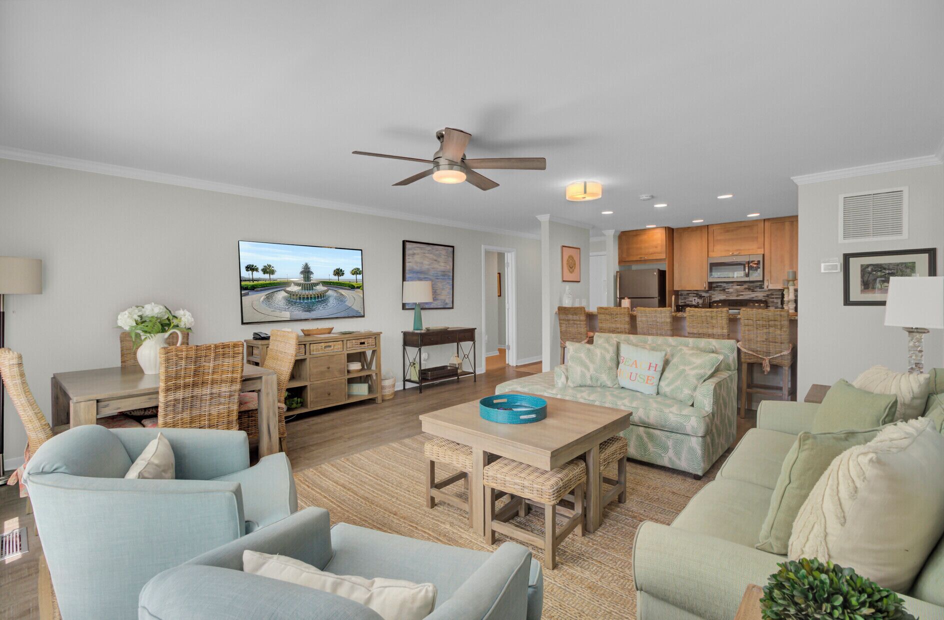 A spacious living room with a large TV, comfortable seating, a dining area, and a kitchen.
