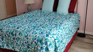 Un dormitorio con colcha de motivos florales, un cuadro de pájaros en la pared y una lámpara de noche.
