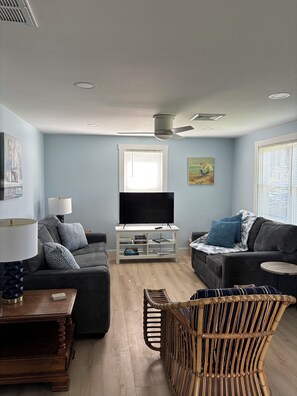Un salon moderne avec deux canapés, un téléviseur et un ventilateur de plafond.