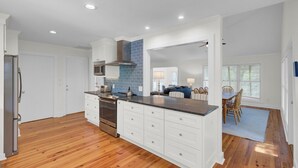 Una cucina moderna con mobili bianchi, piano cottura in acciaio inossidabile e paraschizzi blu.