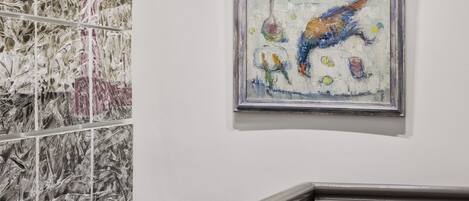 A staircase with a handrail and a wall with a framed abstract painting.