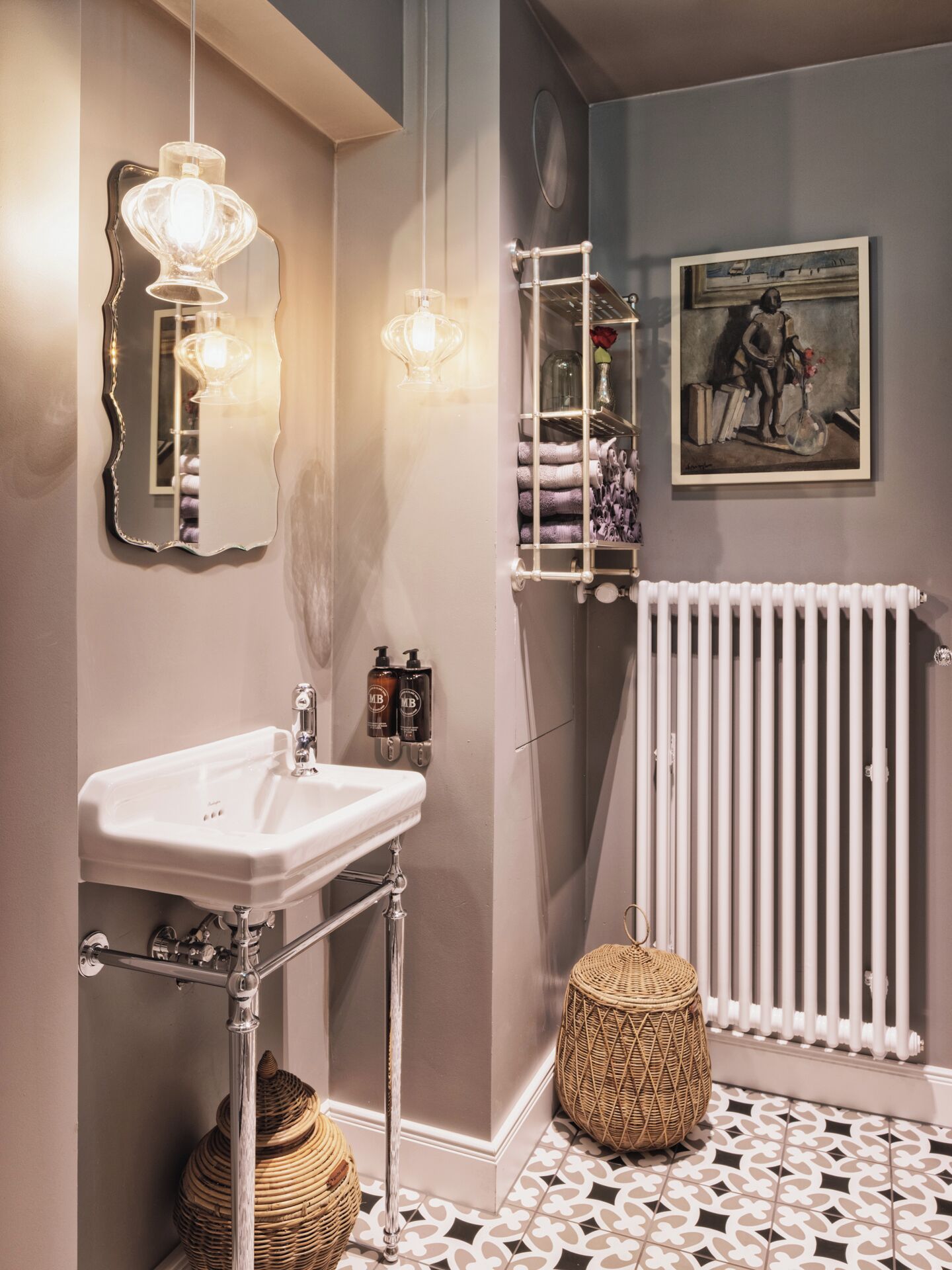 Un baño con un lavabo blanco, un espejo, un radiador y un cuadro en la pared.