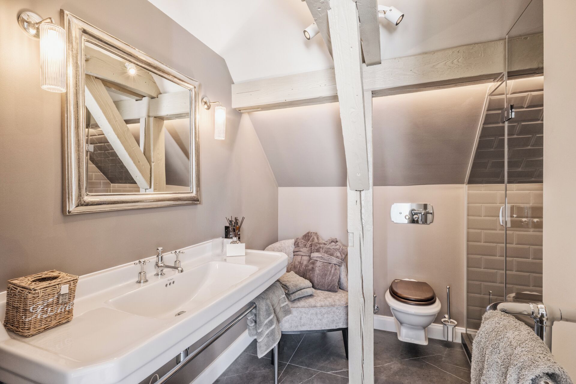 Une salle de bain moderne dotée d’un grand miroir, de deux vasques, d’une douche et de toilettes.