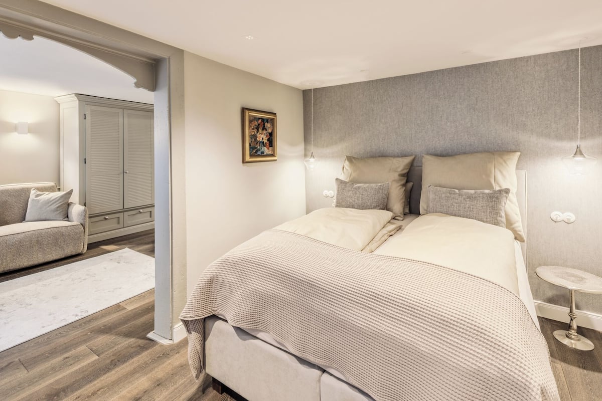Un dormitorio con una cama grande, una mesita de noche, una silla y un armario.