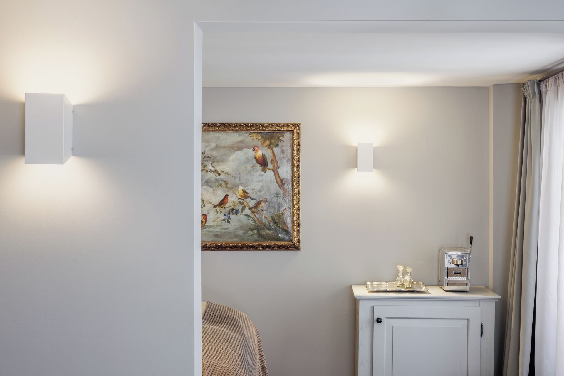 Quarto com quadro de pássaros, máquina de café e armário.