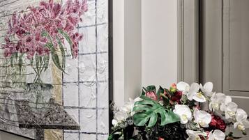 Una pared con una pintura de textura que muestra flores rosas y un jarrón con orquídeas blancas y rojas.