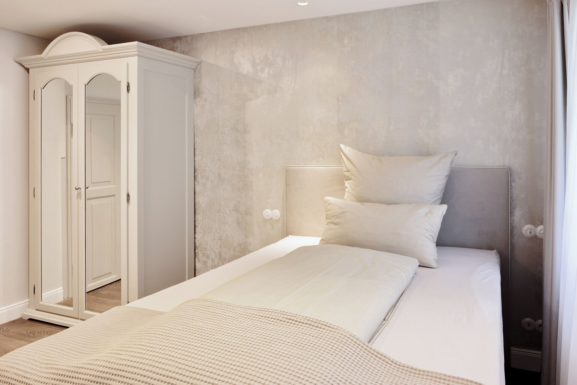 Ein Schlafzimmer mit einem Bett, einem Kleiderschrank und einer strukturierten Wand.
