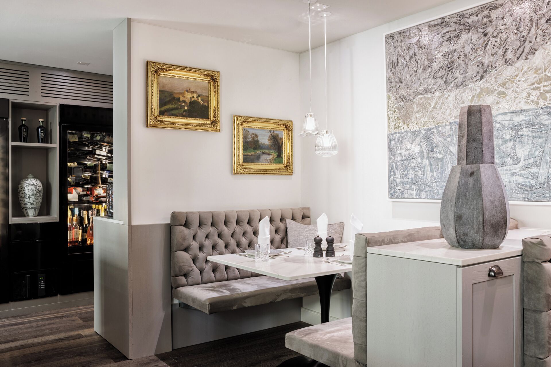 Een modern interieur met een zithoek, een bar met flessen en kunstwerken aan de wanden.