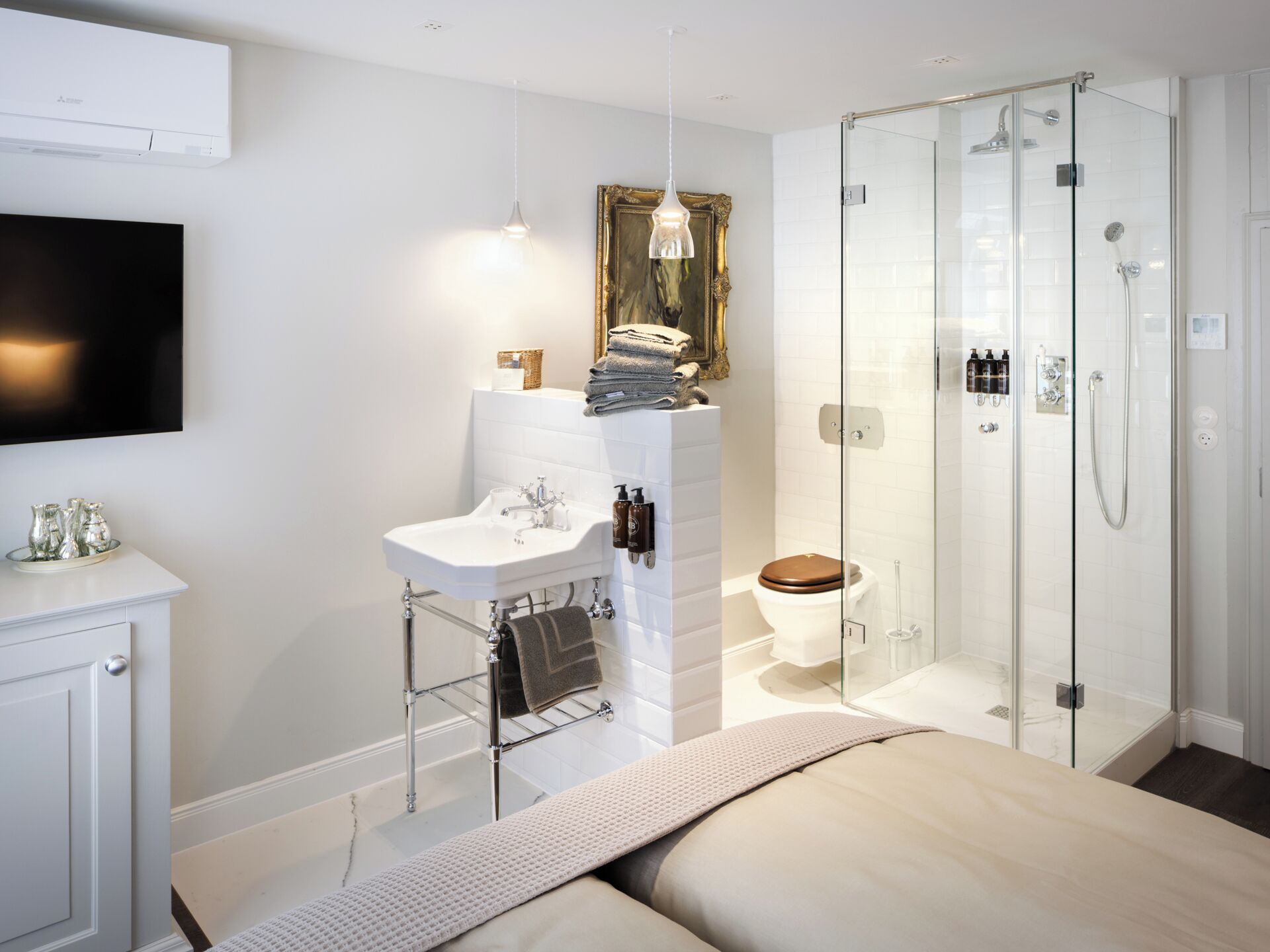 A modern bathroom with a glass-enclosed shower, a white sink, and a mounted television.