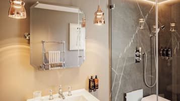 Un baño moderno con un espejo grande, un lavamanos blanco y una cabina de ducha de vidrio.