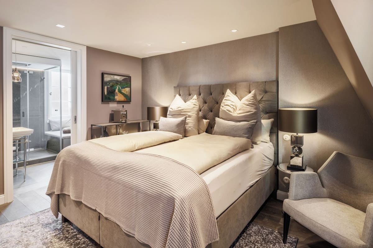 Habitación de hotel moderna con una cama grande, un escritorio y zona de ducha.