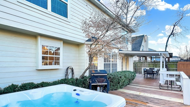 Un jardin avec un jacuzzi, une terrasse en bois, du mobilier d’extérieur et un barbecue.