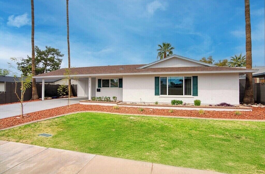 A modern single-story house with a flat roof, large windows, and a covered patio area.