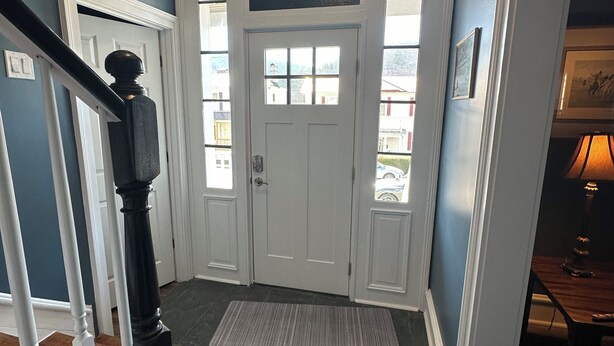A hallway with a white door, a wooden staircase, and a rug on the floor. - Newly renovated 3 bed 2 bath house in Clifton Forge, Va (Clifton Forge)