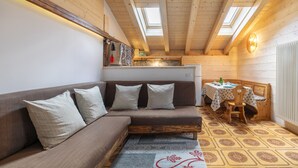 A cozy room with a wooden ceiling, a sofa with cushions, a patterned rug, and a small table with a chair. - Garden Apartment Relax (Barco)