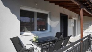 Eine Terrasse im Freien mit Tisch, Stühlen, einem Fenster und einer Holzpergola.