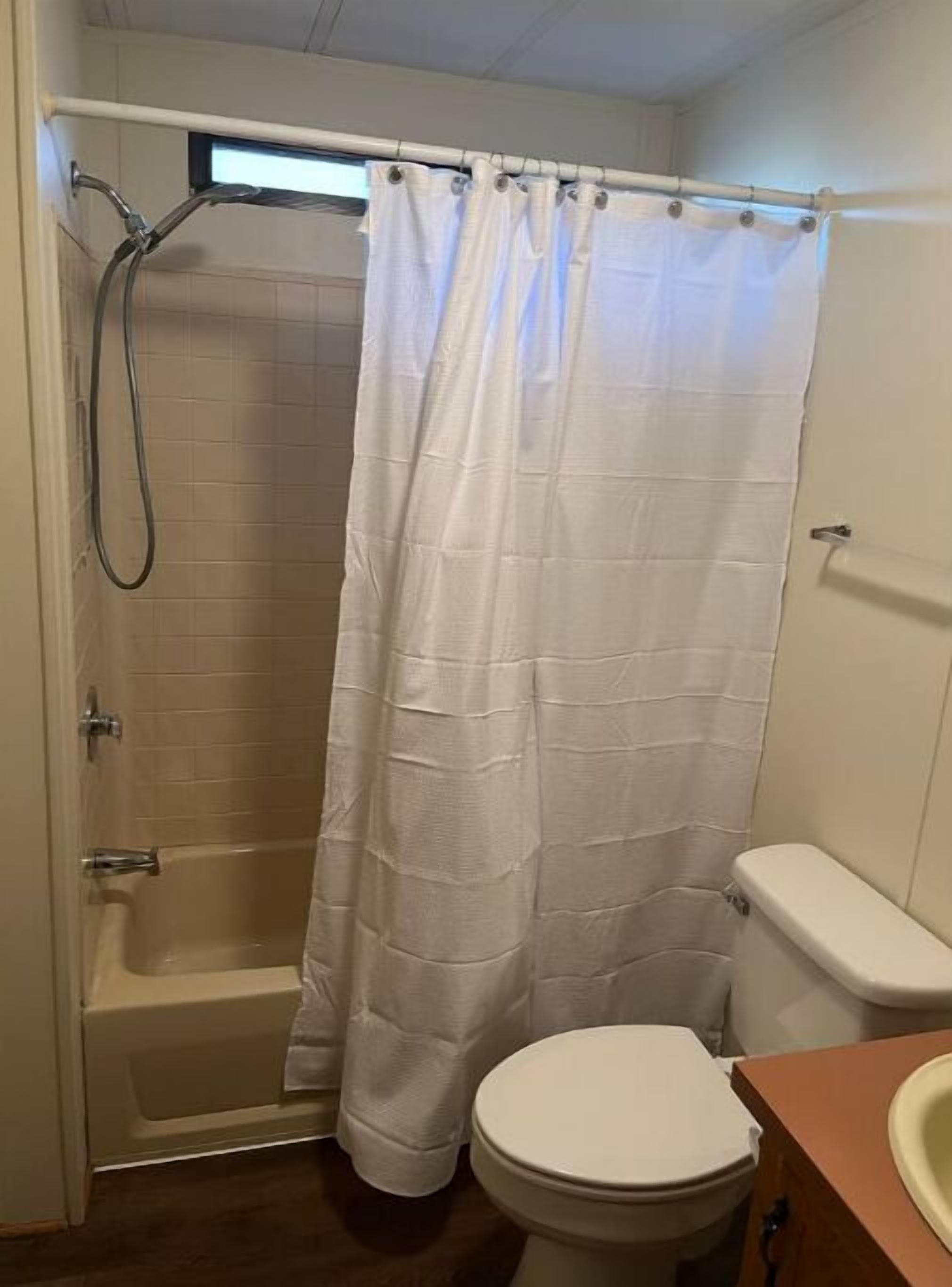Een badkamer met douche, toilet en wastafel.