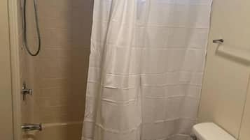 Een badkamer met douche, toilet en wastafel.