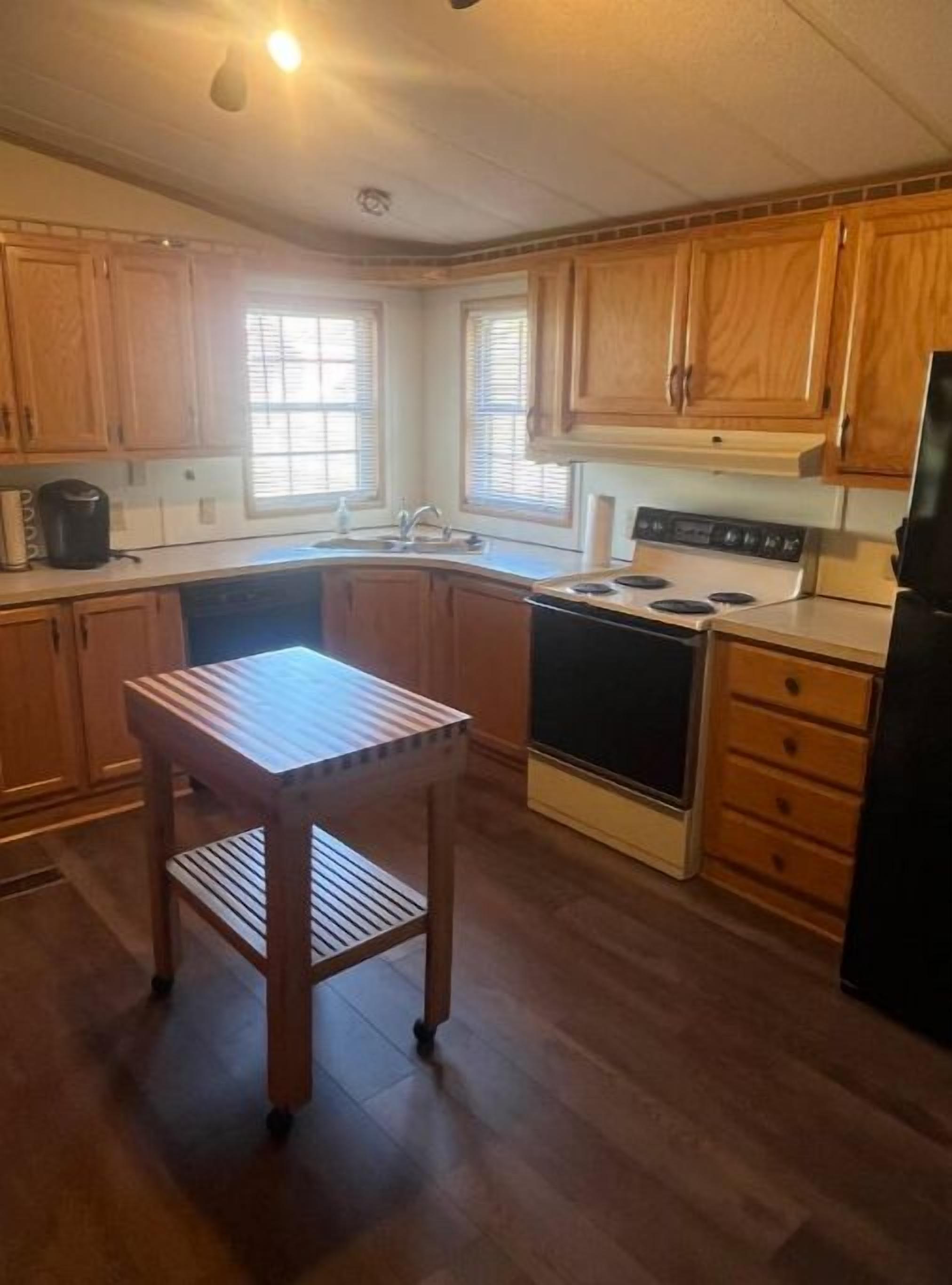 Una cucina con mobili in legno, un piano cottura, un lavello e un piccolo tavolo di legno.