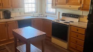 Una cucina con mobili in legno, un piano cottura, un lavello e un piccolo tavolo di legno.
