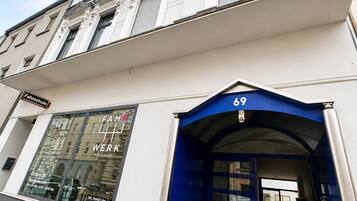 Ein Gebäude mit blauem Eingang, einem sichtbaren Schaufenster mit Fahrrädern und einem Schild, das eine Schule kennzeichnet.