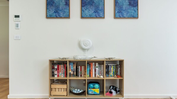 A bookshelf with books, a decorative shell, and a small dog figurine.