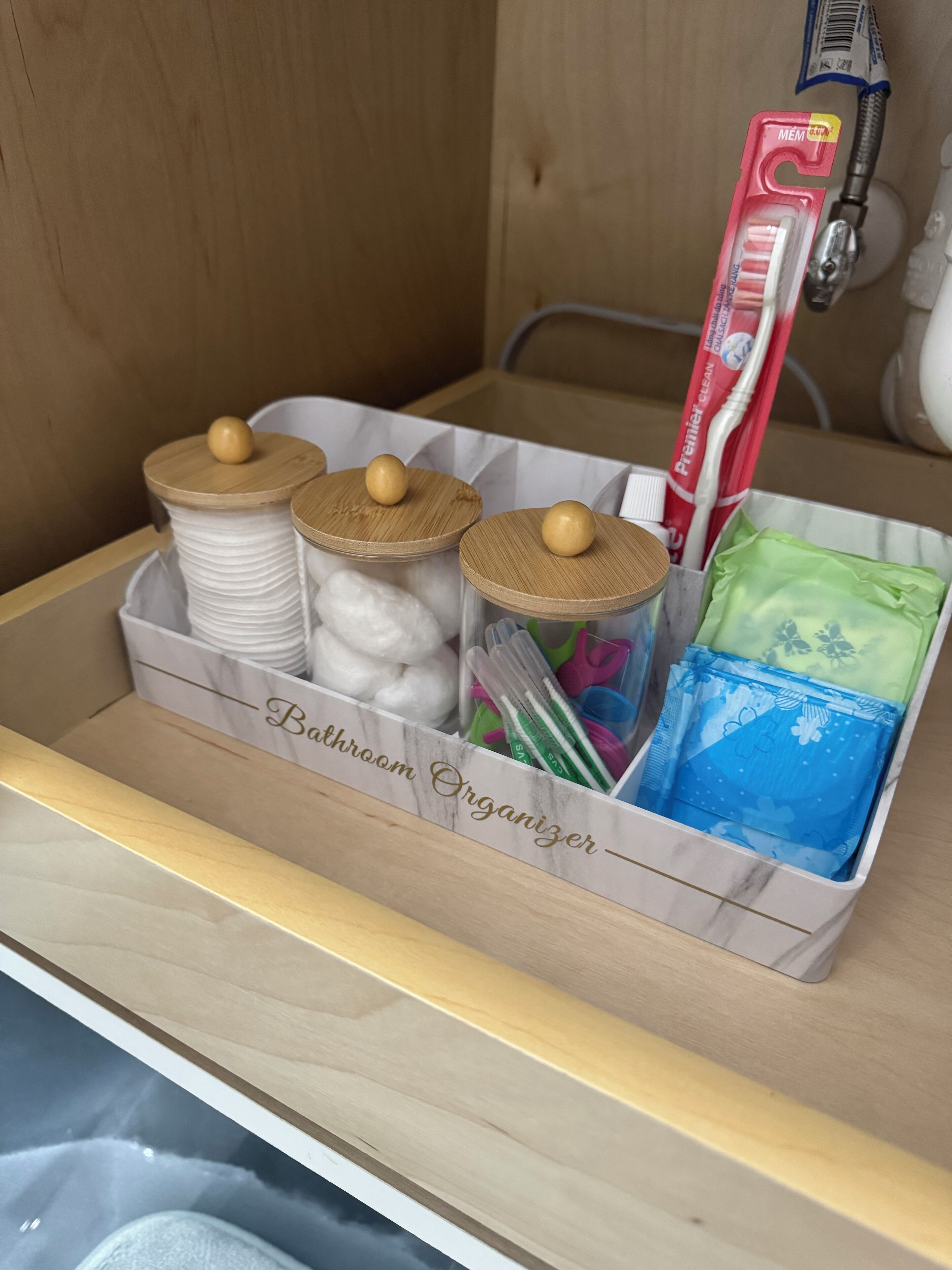 A bathroom organizer with jars, a toothbrush, and toiletries.