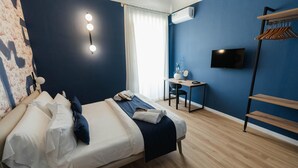A bedroom with a bed, bedside table, chair, TV, and a wardrobe.