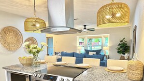 A modern kitchen with granite countertops, a built-in oven, and a dining area with a blue sofa.