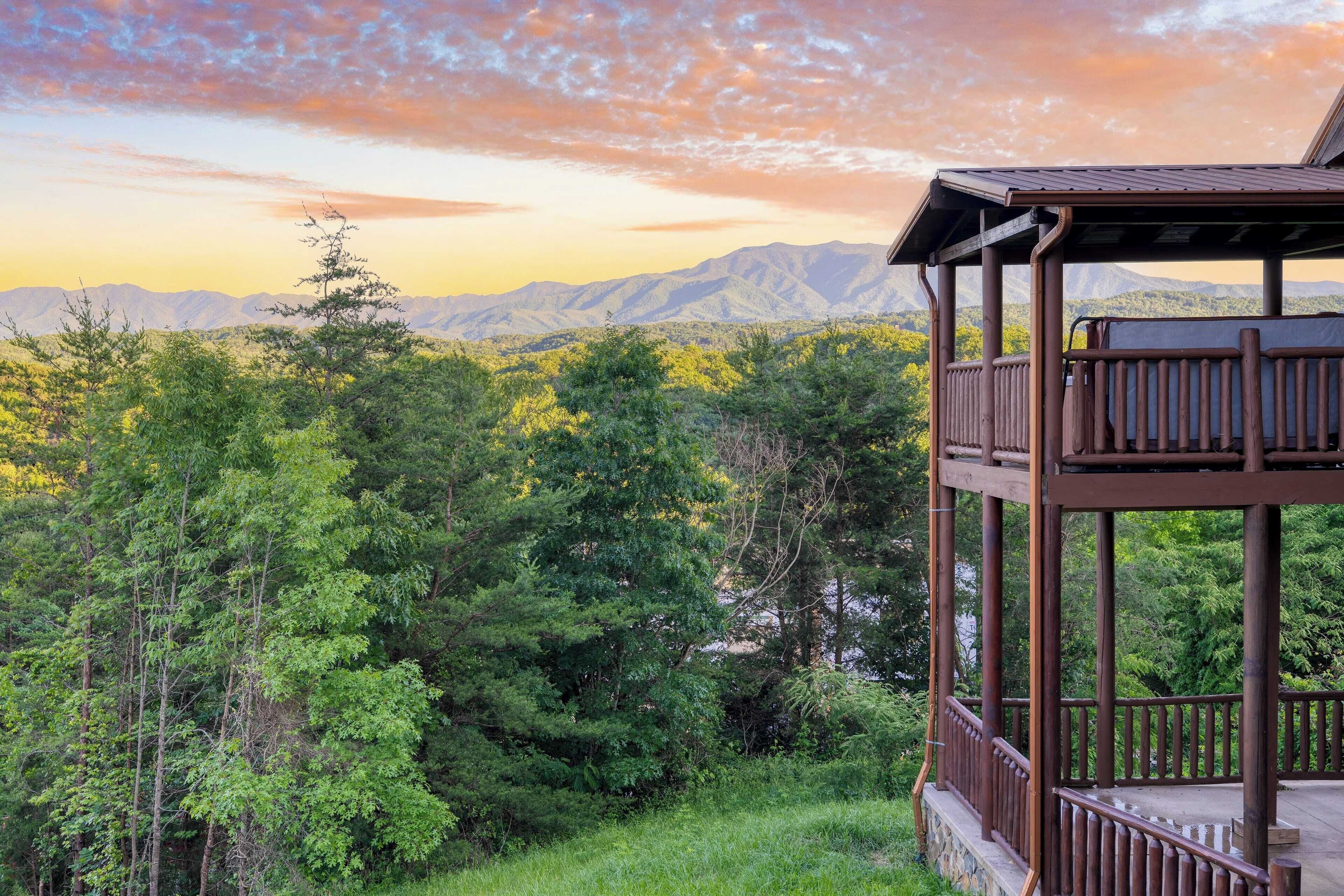 A wooden deck with a view of a forest and mountains.