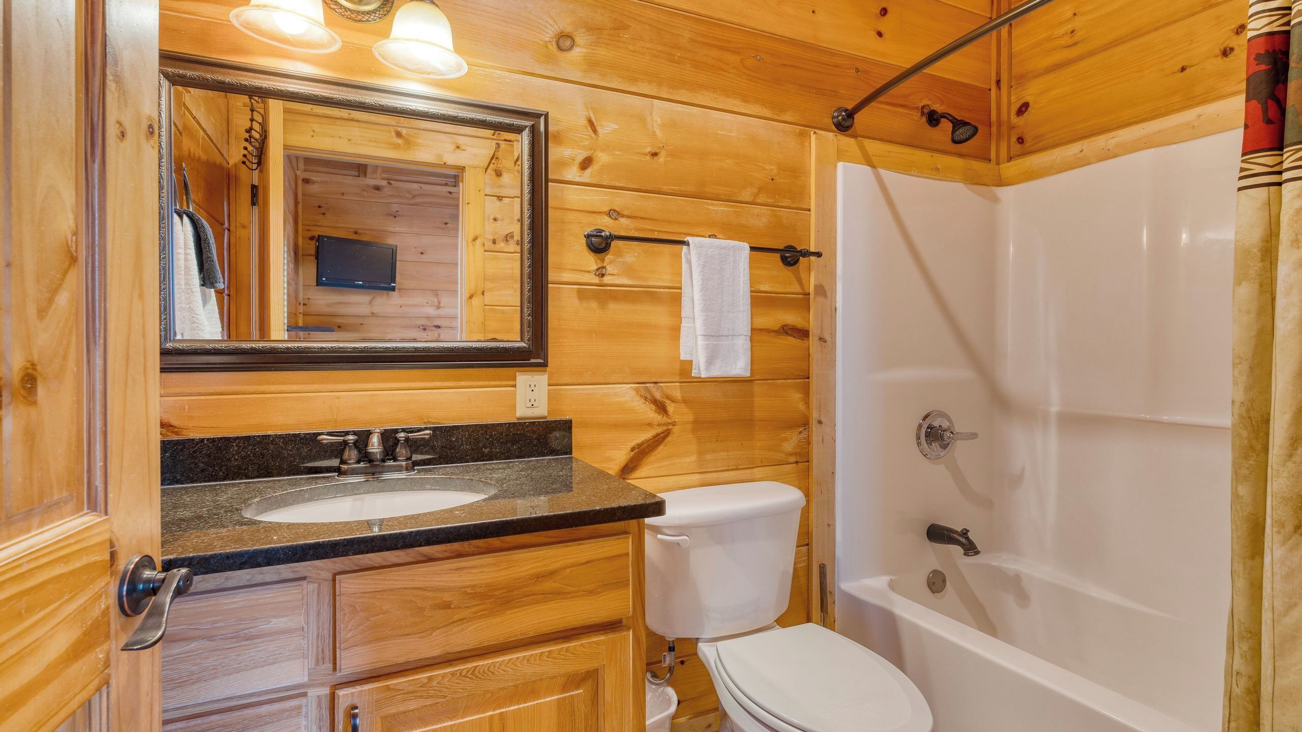 A wooden cabin bathroom with a sink, toilet, and shower.