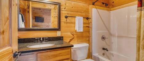 A wooden cabin bathroom with a sink, toilet, and shower.