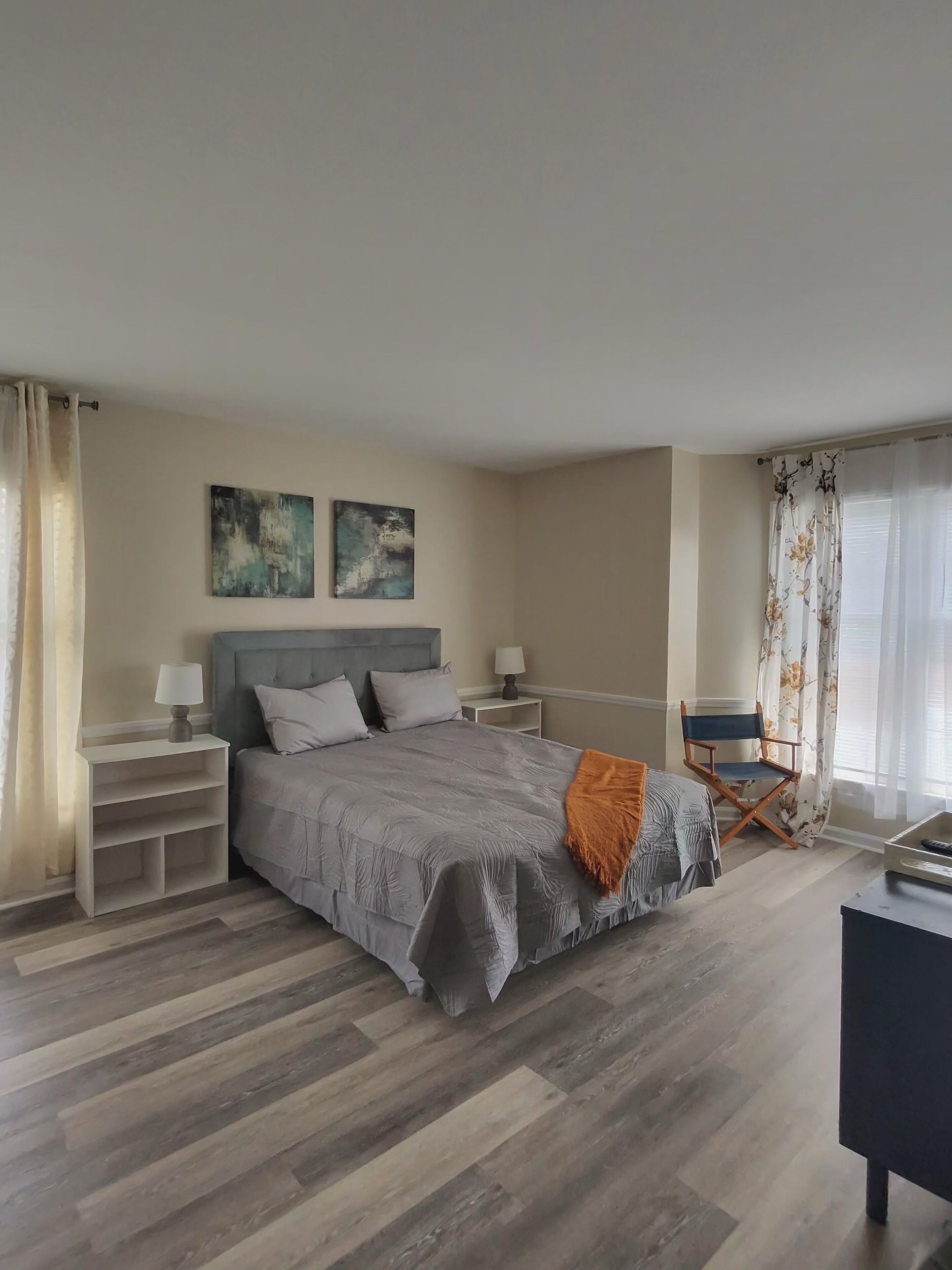 A bedroom with a bed, nightstands, a chair, and artwork on the wall.