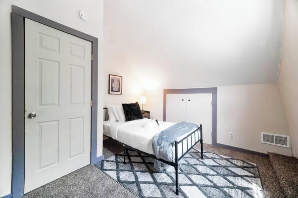 Un dormitorio con cama, mesita de noche, armario empotrado y una puerta.