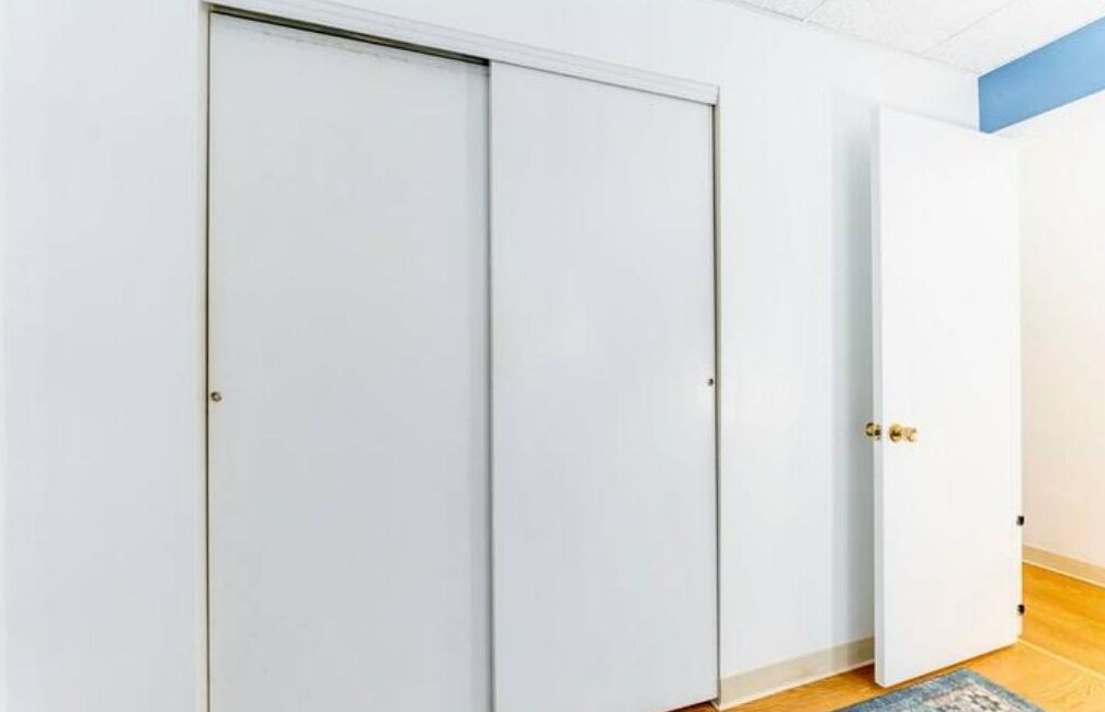 A room with a closed sliding door, a partially open door, and a wooden floor.